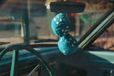 Blue fuzzy dice hanging from a rearview mirror. 